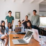 A group of people sitting around a table with laptops.