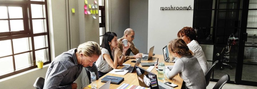 A group of people sitting at a table with laptops.